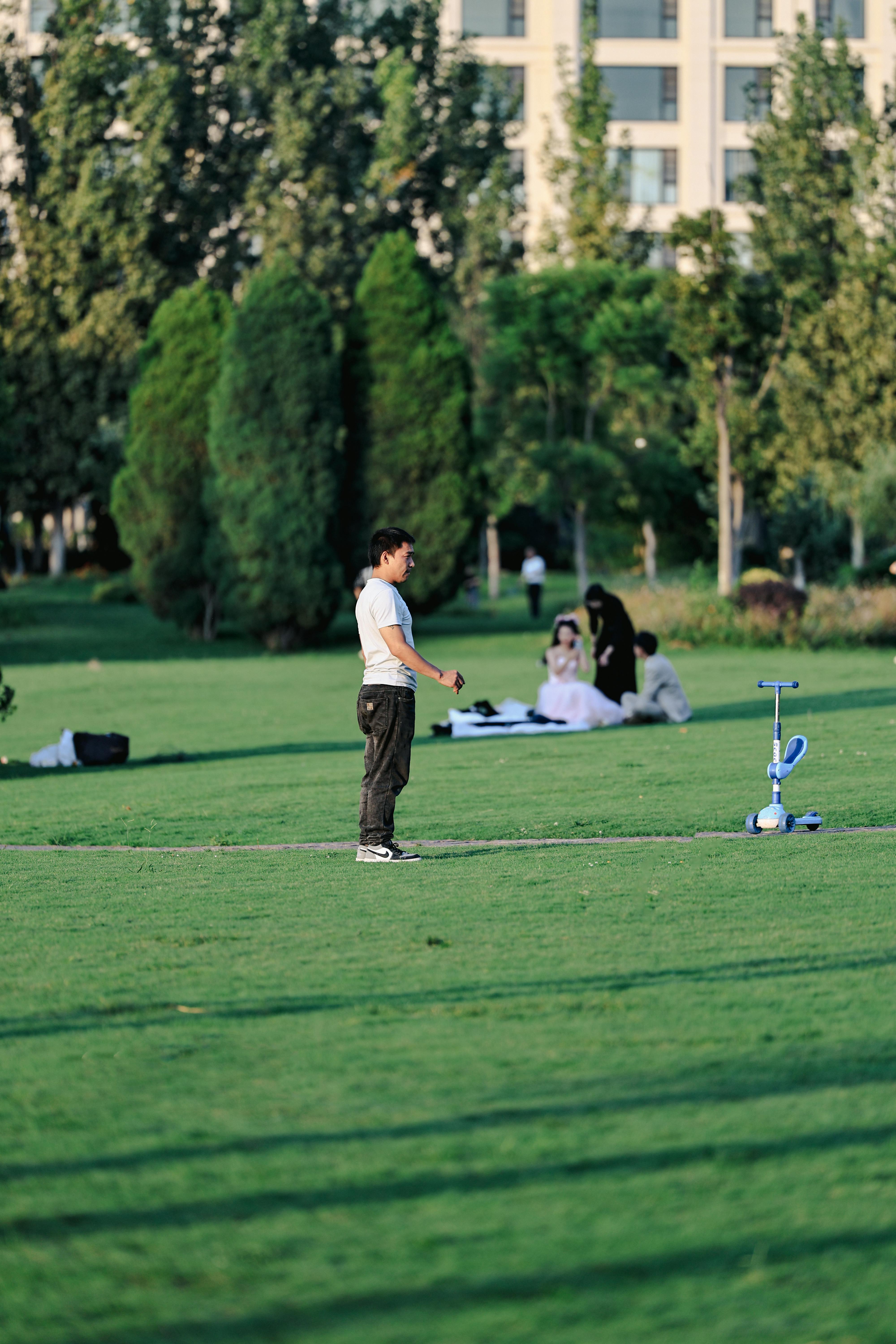 A man practices his golf swing on a lush green lawn in summer.