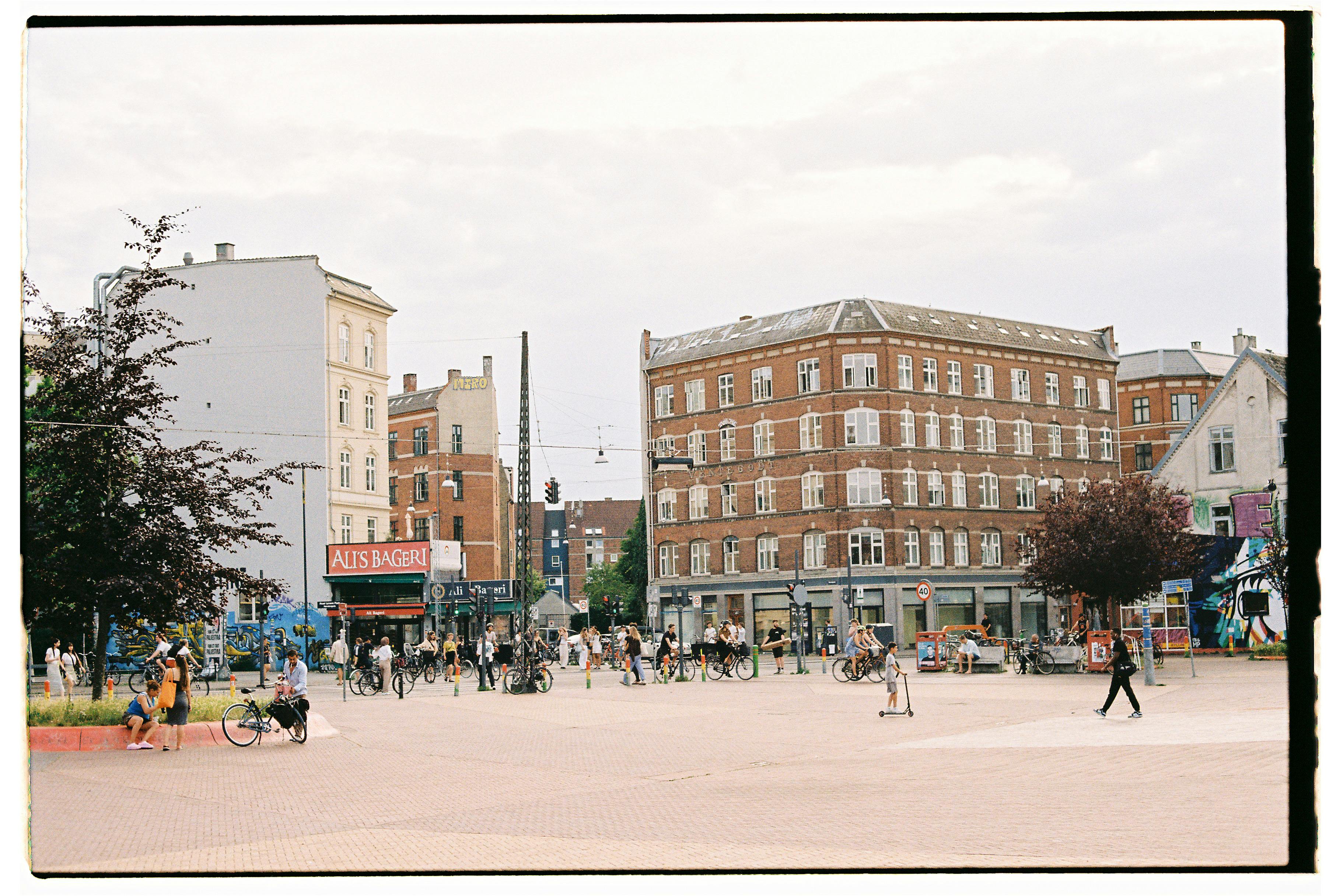 Street view of a bustling urban square with historic architecture and people engaging in daily activities.