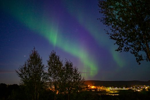 Stunning view of Northern Lights dancing over Karasjok, Norway, under a clear starry night sky.