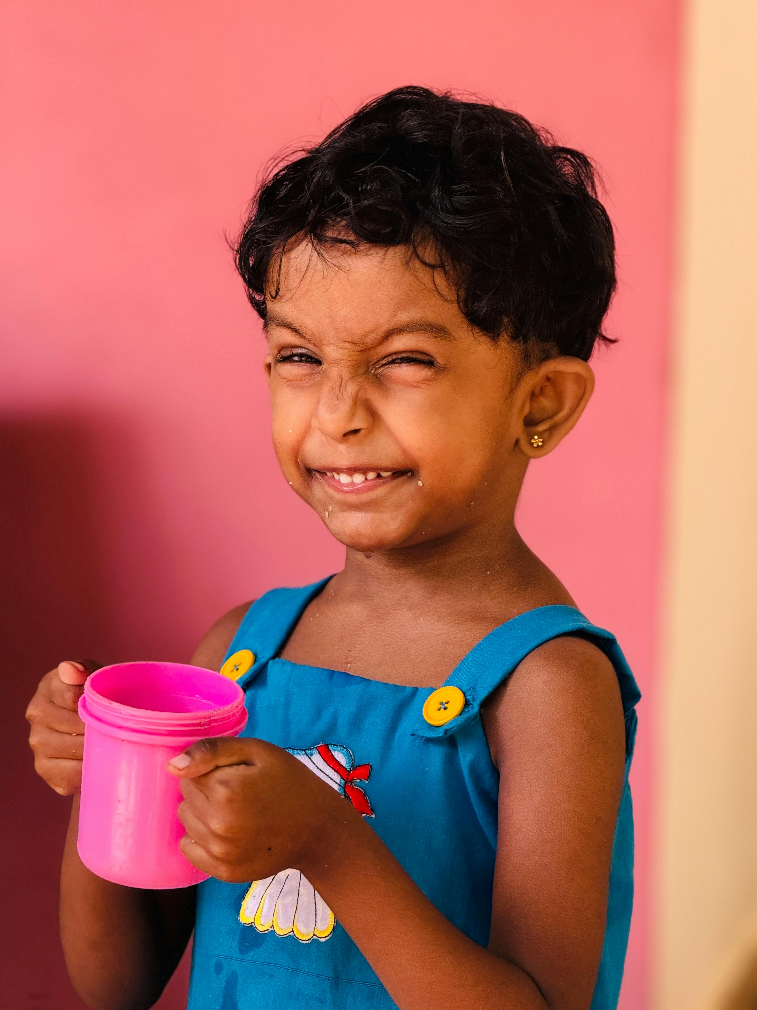 a young girl holding a cup and smiling