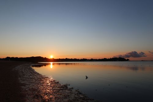 Free Serene sunset scene at Stamford's coast, showcasing a tranquil beach and vibrant sky reflection. Stock Photo