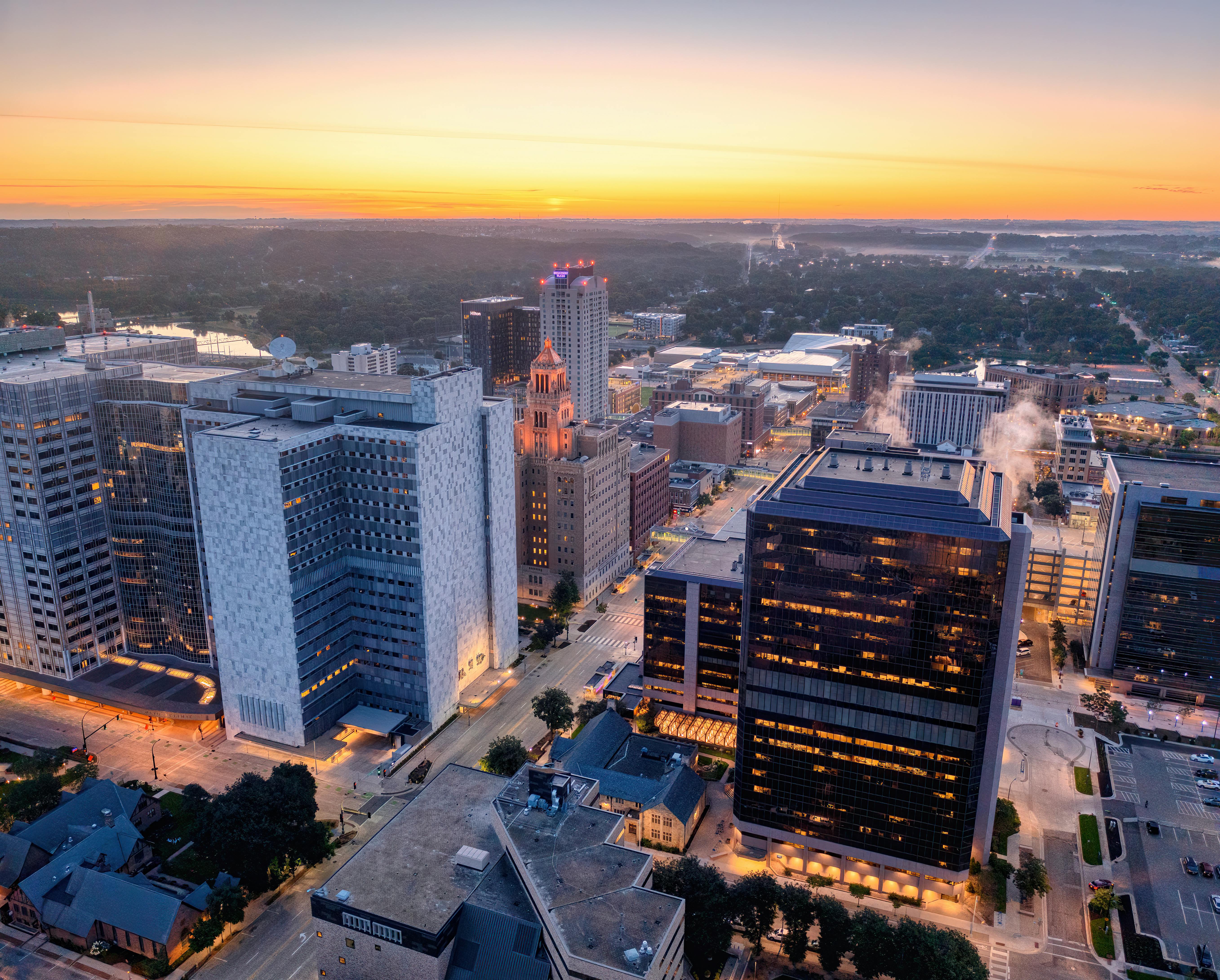 Aerial view of Rochester, MN skyline at sunrise with modern buildings and vibrant colors.