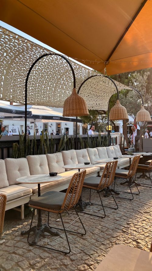 Free Stylish outdoor cafe with modern chairs and cozy seating under decorative umbrellas. Stock Photo