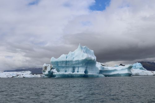 Free Spectacular view of a blue iceberg floating in a cold sea amid overcast skies. Stock Photo