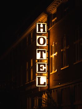 A bright hotel sign glowing on a building facade during nighttime.