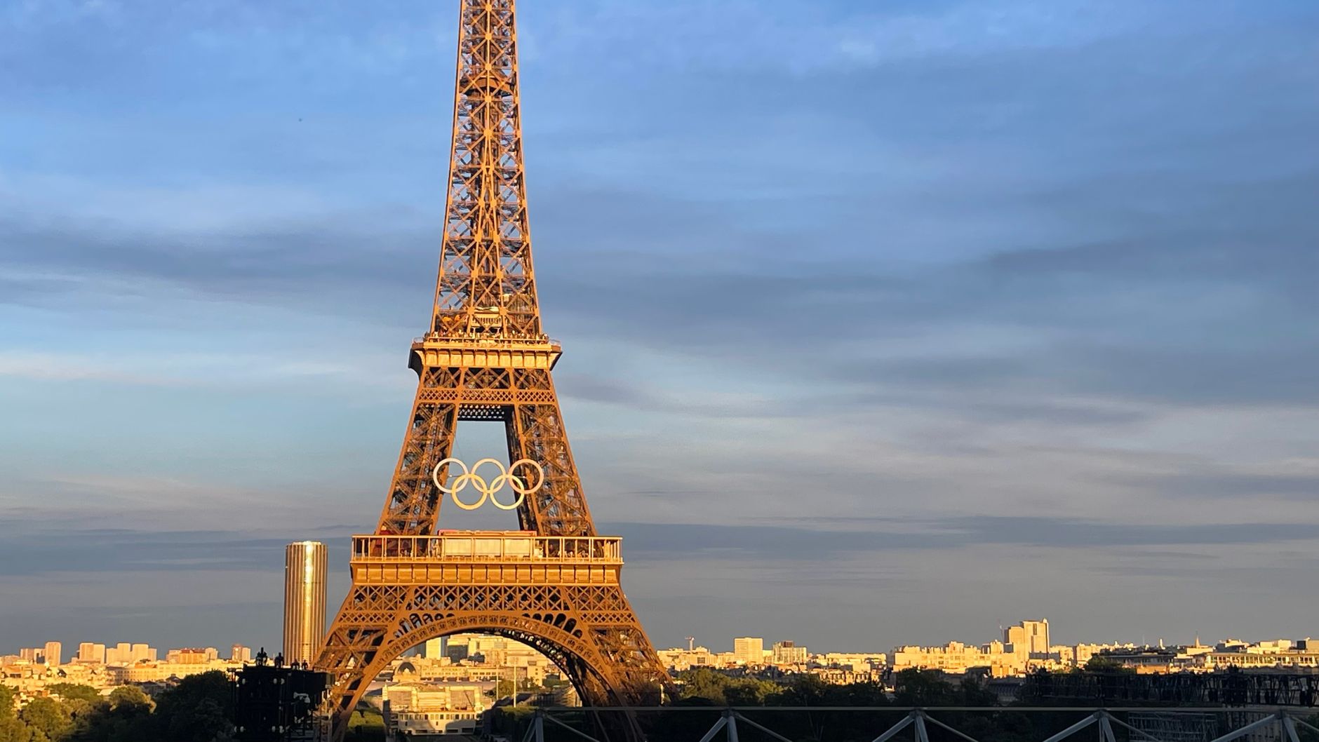 The Eiffel Tower adorned with Olympic rings at sunset, Paris skyline view.