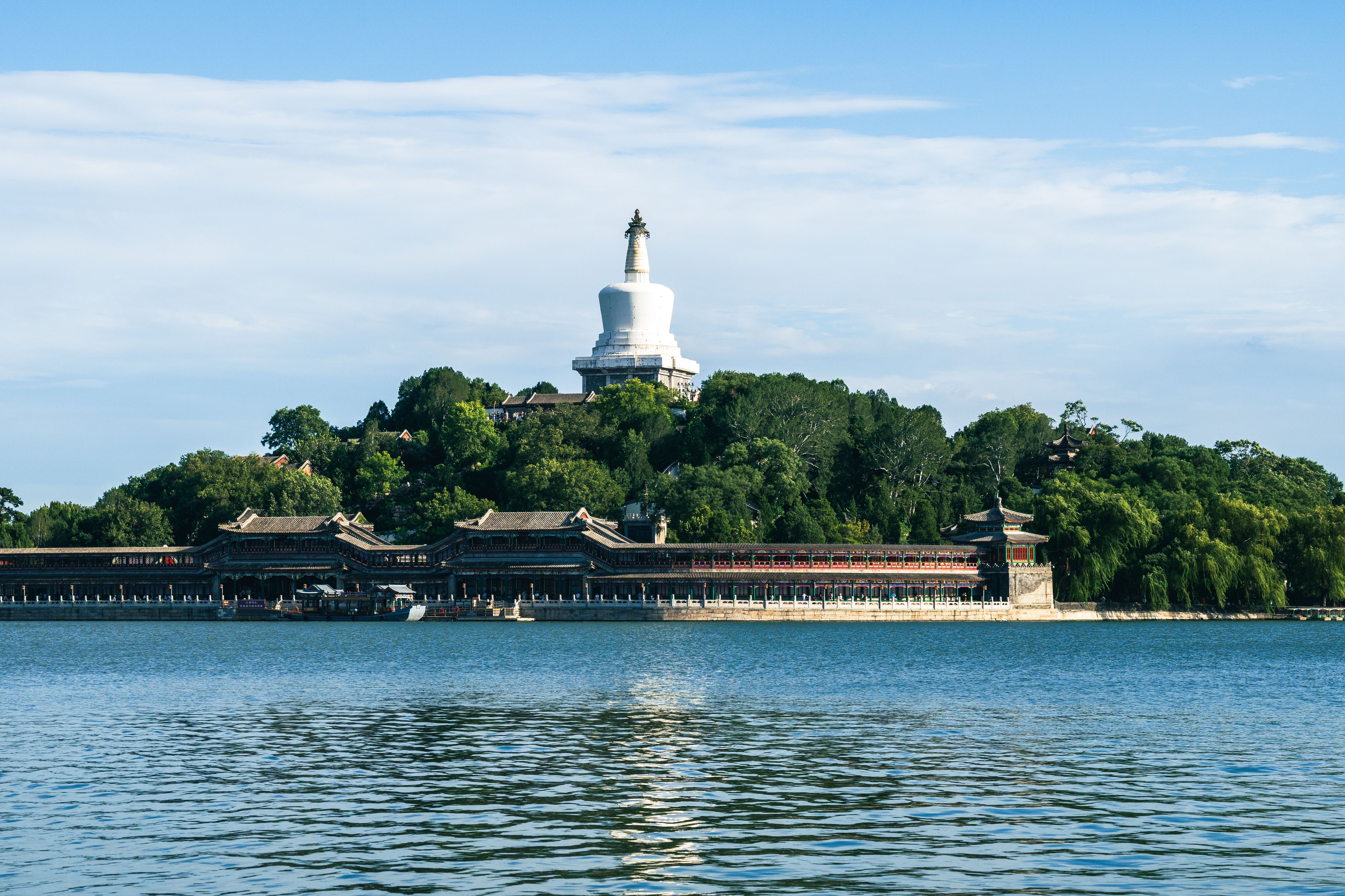 Scenic view of the iconic White Pagoda in Beihai Park, Beijing, with surrounding greenery and water.
