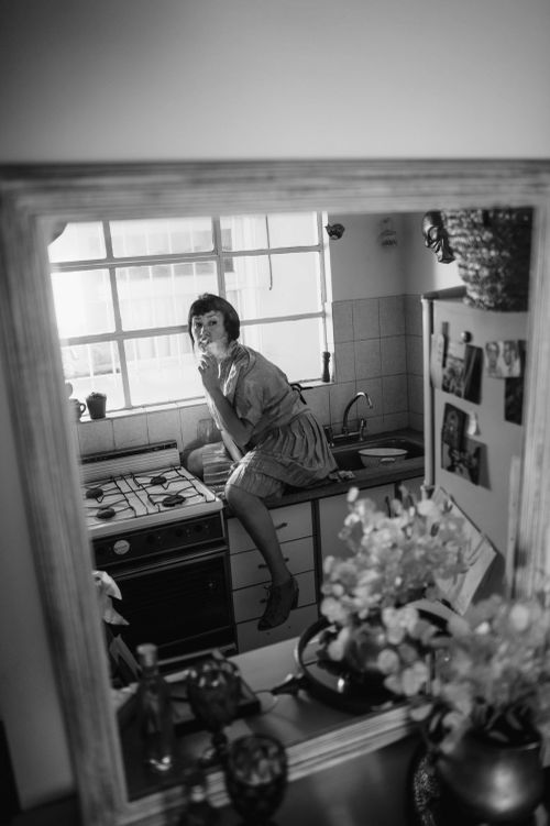 Free Black and white reflection of a woman sitting in a vintage kitchen setting. Stock Photo