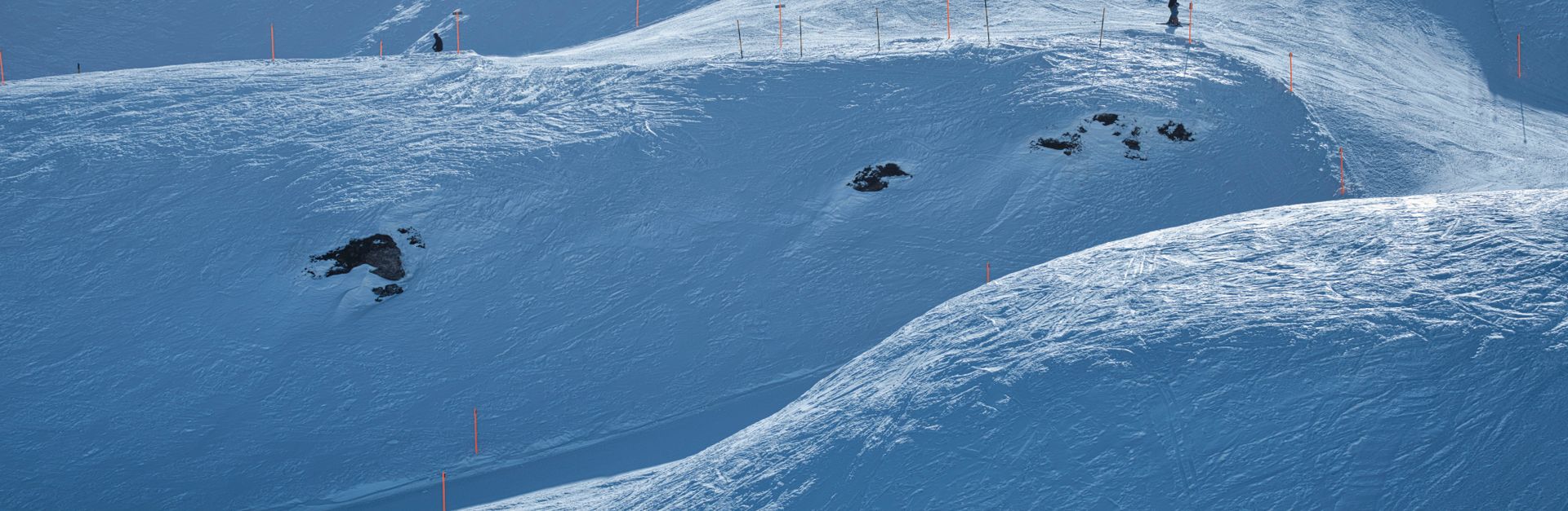 Scenic view of a snowy ski resort slope with skiers and chairlifts under a clear winter sky.