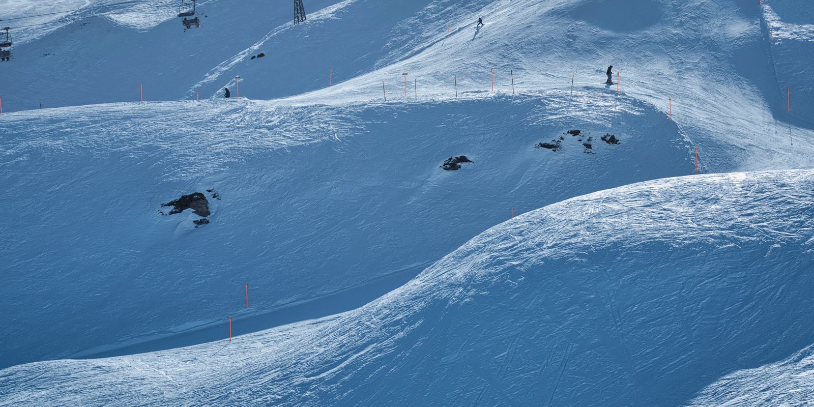 A snowy ski resort slope with skiers and chairlifts under a clear sky