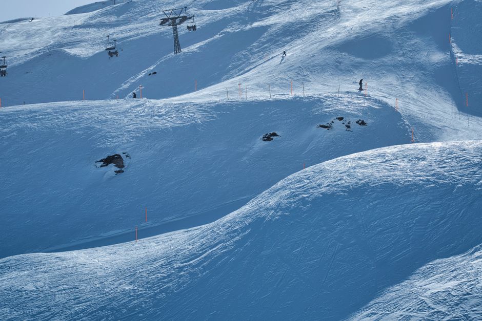 Scenic view of a snowy ski resort slope with skiers and chairlifts under a clear winter sky.