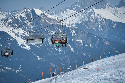 Skiers ride a lift in a snowy alpine ski resort with stunning mountain views.