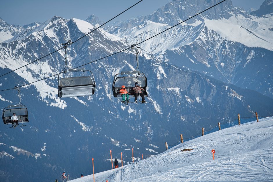 Skiers ride a lift in a snowy alpine ski resort with stunning mountain views.
