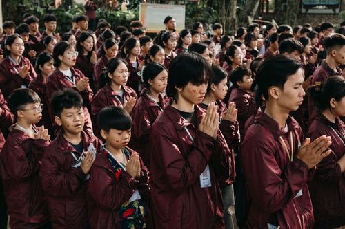 Free A large group of young people dressed in maroon jackets engaged in prayer outdoors. Stock Photo