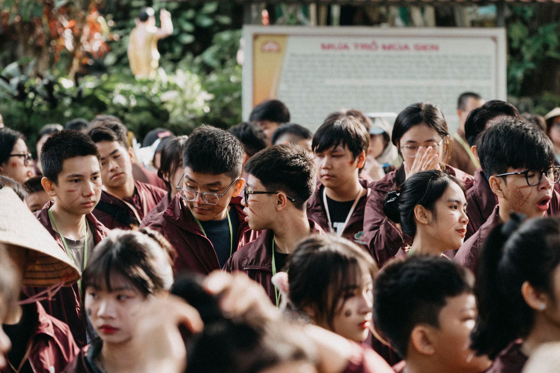 A large group of young adults socializing outdoors, wearing matching attire.