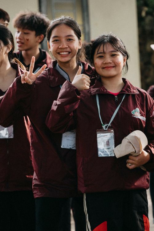 Free Smiling teenagers in maroon jackets posing outdoors, expressing joy and togetherness. Stock Photo