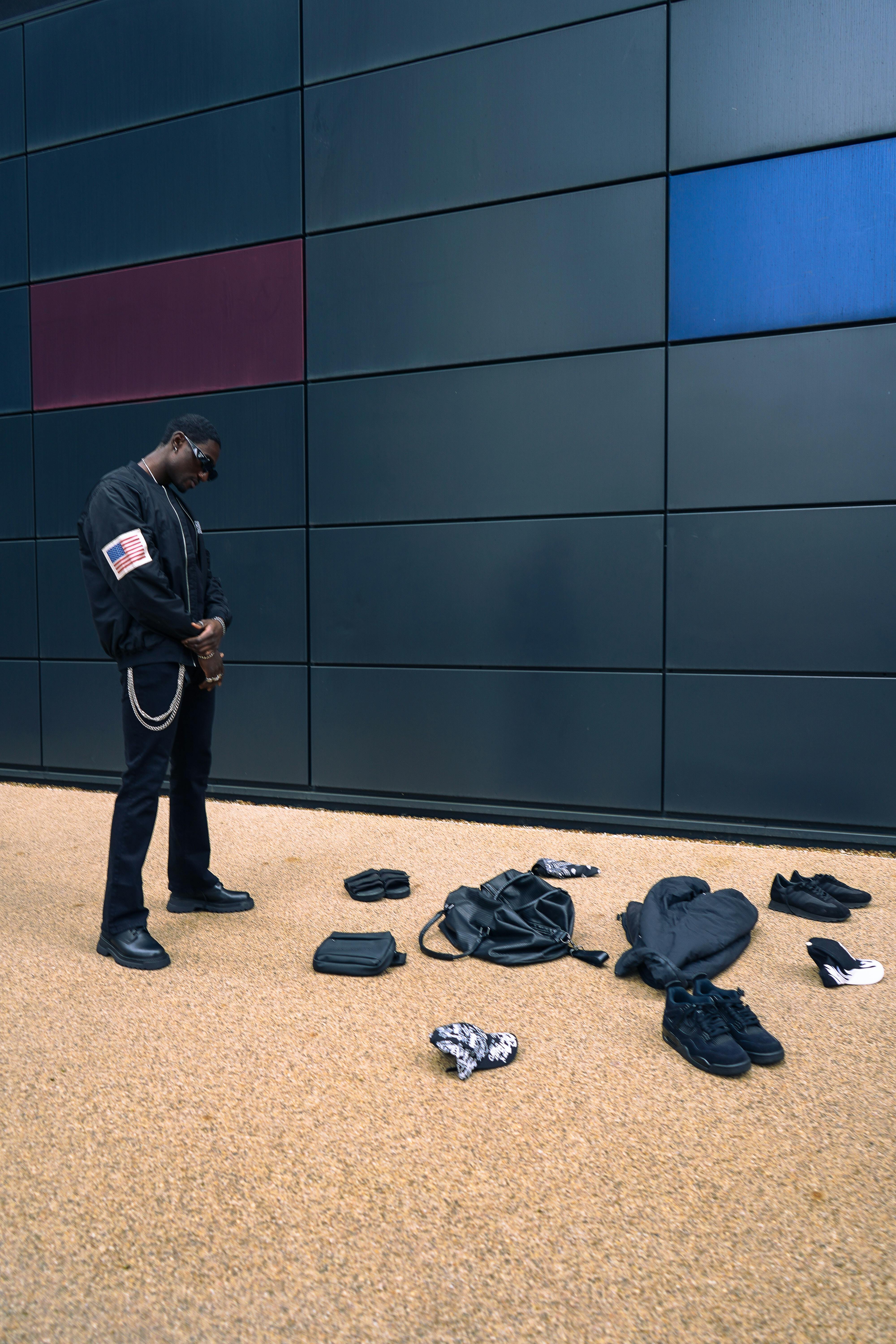 a man standing in front of a wall with clothes and shoes