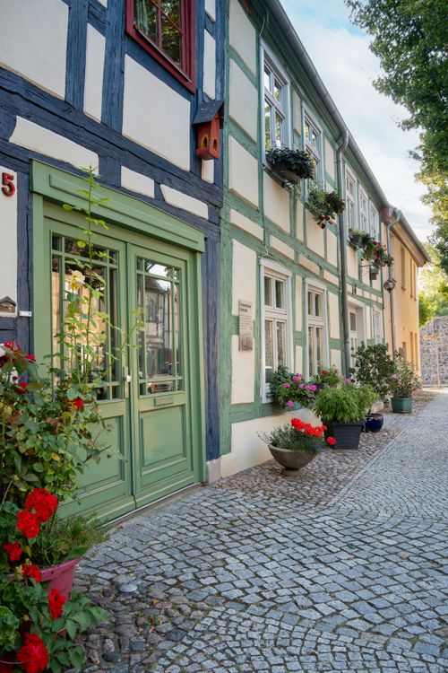 Free Beautiful timber-framed houses with vibrant flowers lining a cobblestone street in daylight. Stock Photo