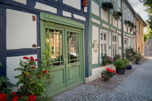 Free Historic timbered house facade adorned with vibrant flowers on a cobblestone street, showcasing European architecture. Stock Photo