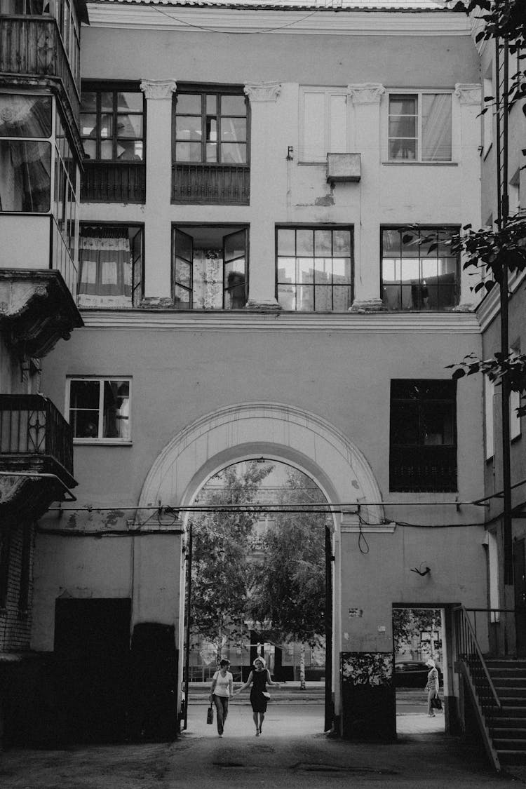 Grayscale Photo Of People Walking Inside The Concrete Building