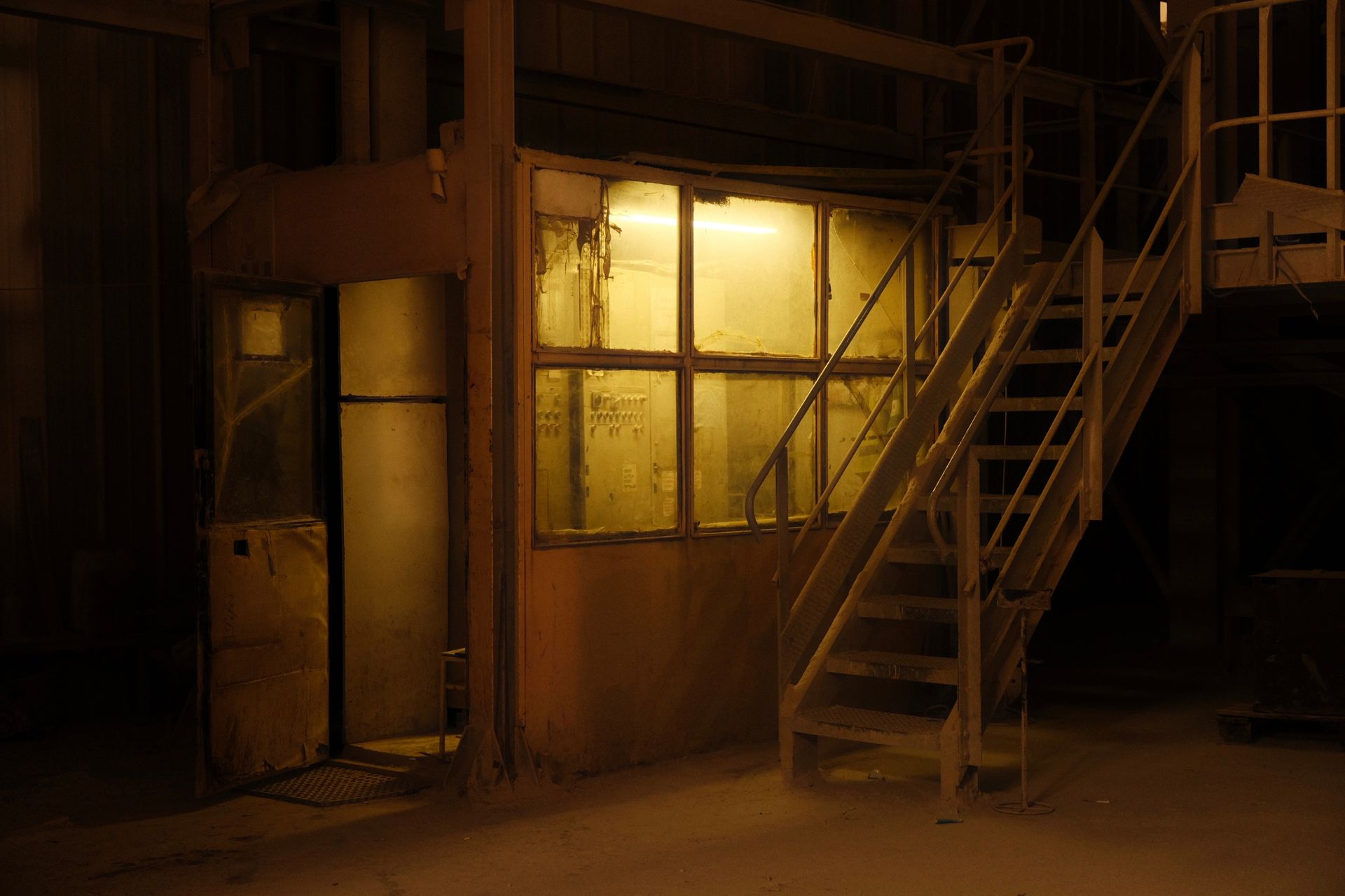 An abandoned industrial interior with a derelict room and eerie lighting, creating a moody atmosphere.