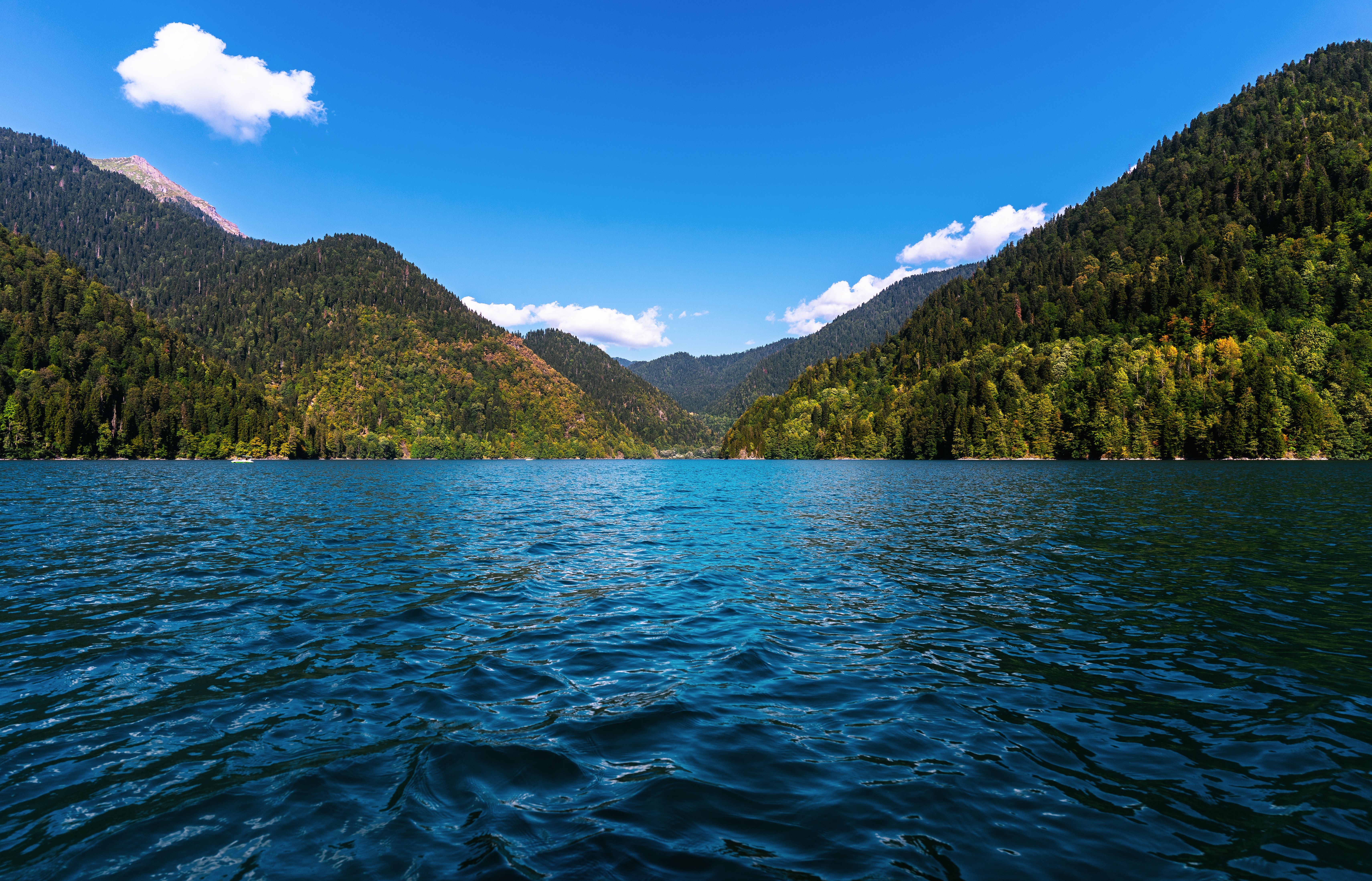 A picturesque mountain lake surrounded by lush forests and clear skies, perfect for travel enthusiasts.