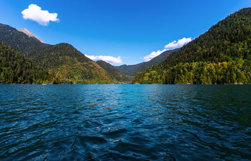 Free A picturesque mountain lake surrounded by lush forests and clear skies, perfect for travel enthusiasts. Stock Photo