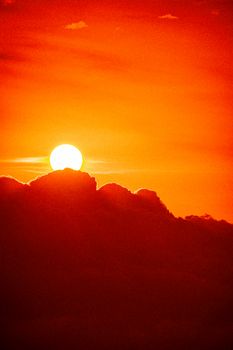 A stunning sunset illuminating bold clouds with a vivid orange and red sky.