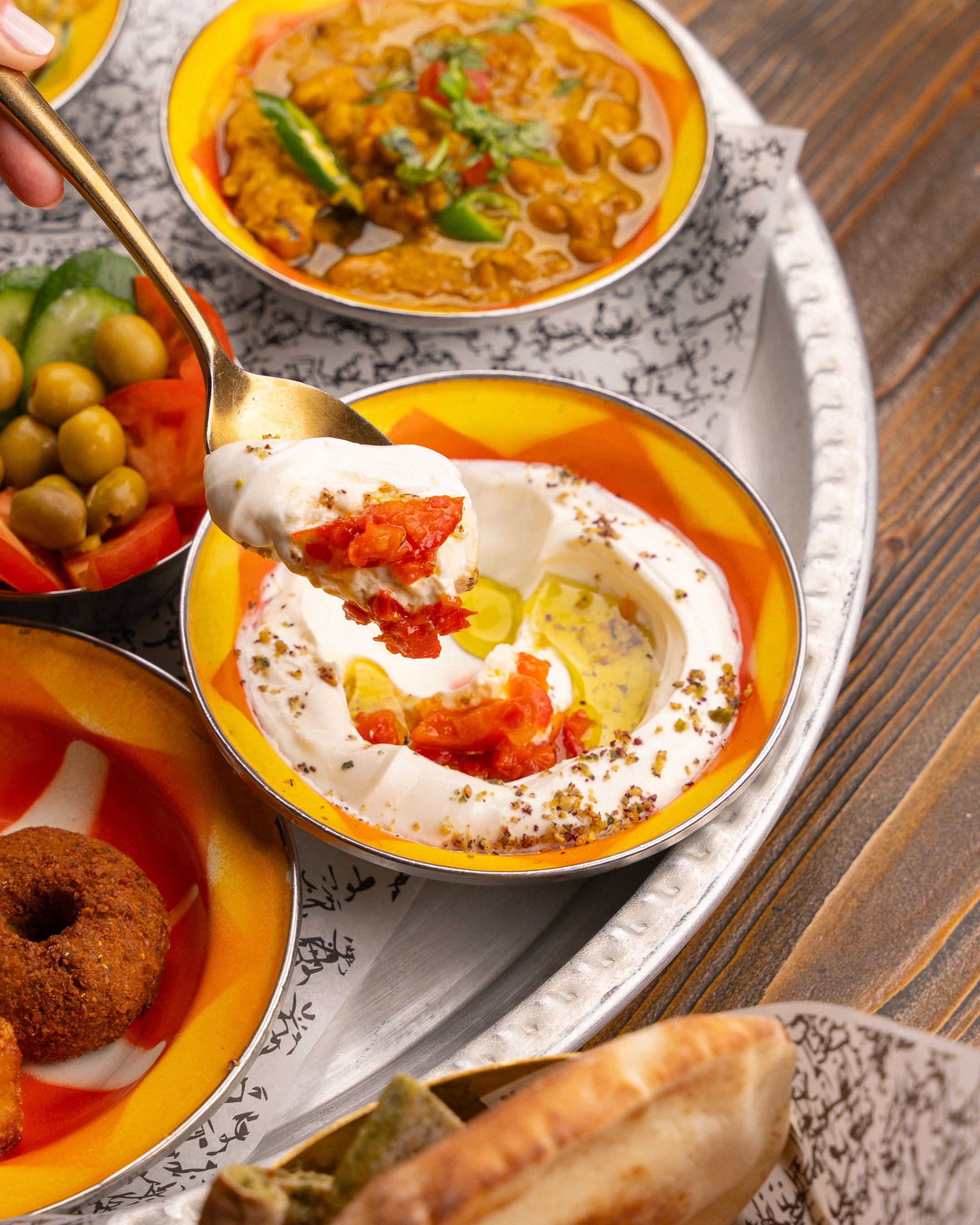 A colorful Middle Eastern mezze platter featuring hummus, falafel, and pickled vegetables.