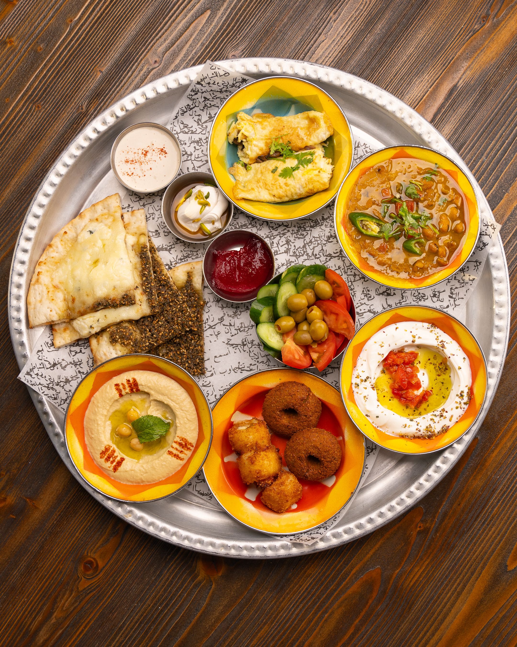 Colorful Middle Eastern mezze platter with dips, bread, and fresh vegetables on a rustic table.