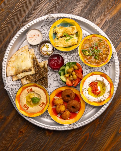 Free Colorful Middle Eastern mezze platter with dips, bread, and fresh vegetables on a rustic table. Stock Photo