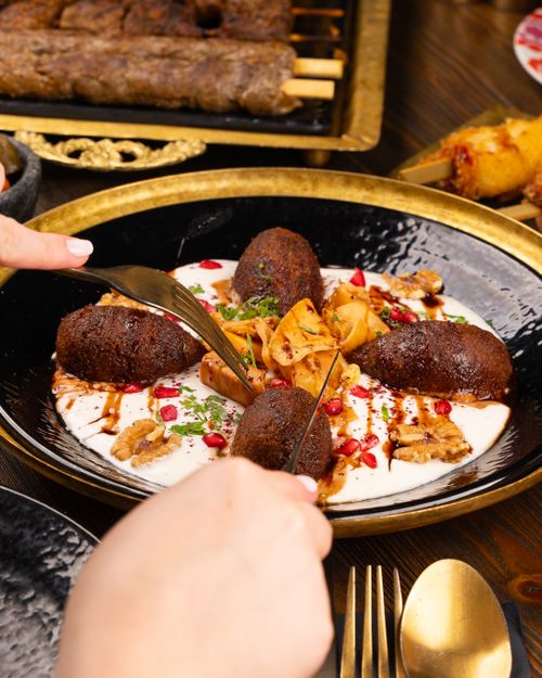 Free Delicious Middle Eastern lamb kibbeh served with creamy sauce and pomegranate seeds. Stock Photo