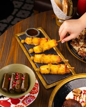 A vibrant Middle Eastern appetizer spread featuring fried skewers and dolma on a wooden table.