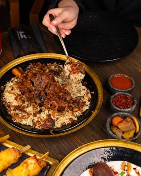 Delicious rice dish with tender meat and spices served with sauces, perfect for a fulfilling meal.