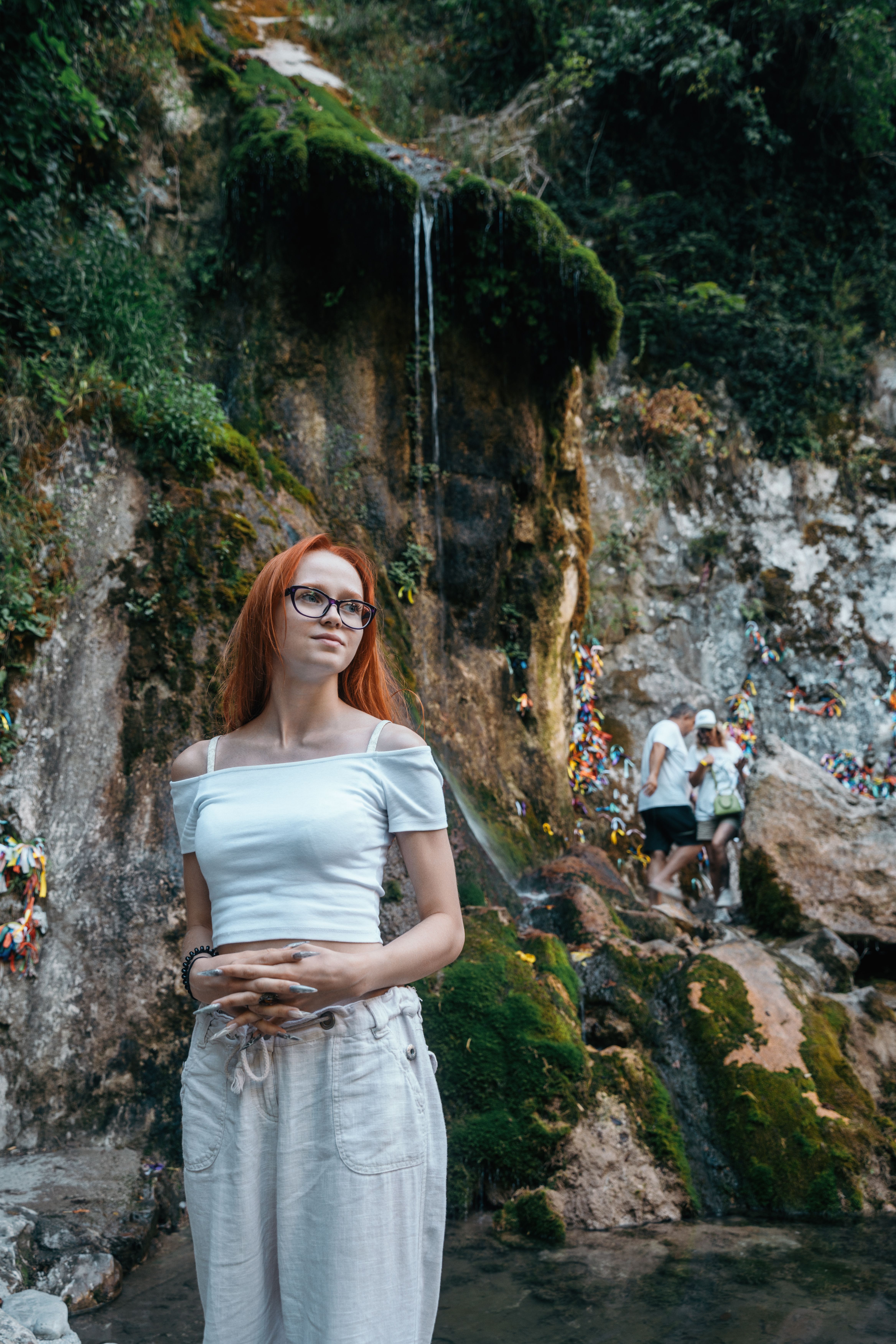 A woman with red hair standing in front of a waterfall · Free Stock Photo