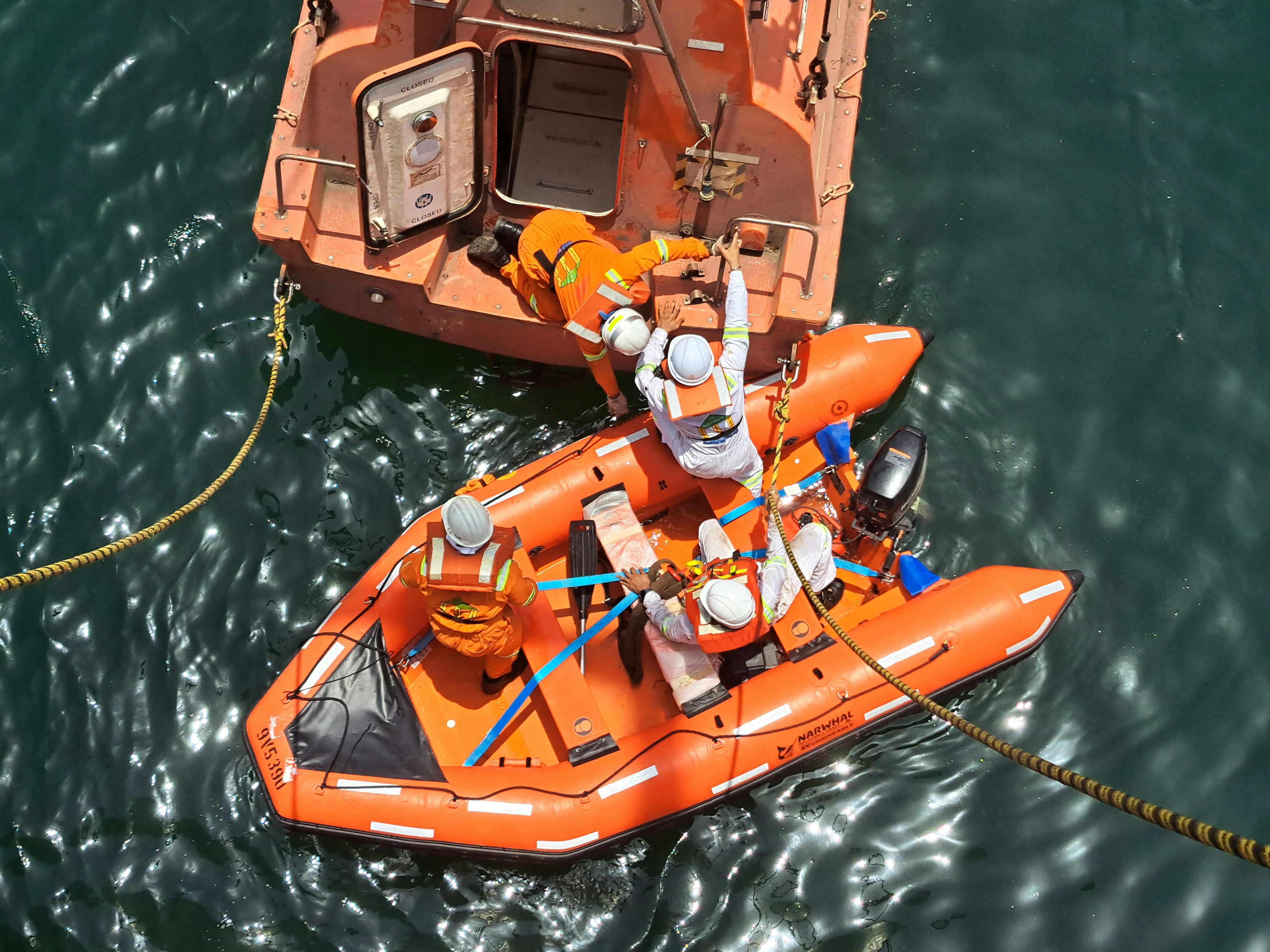 Aerial view of a maritime rescue crew transferring a person between an inflatable boat and a rescue vessel