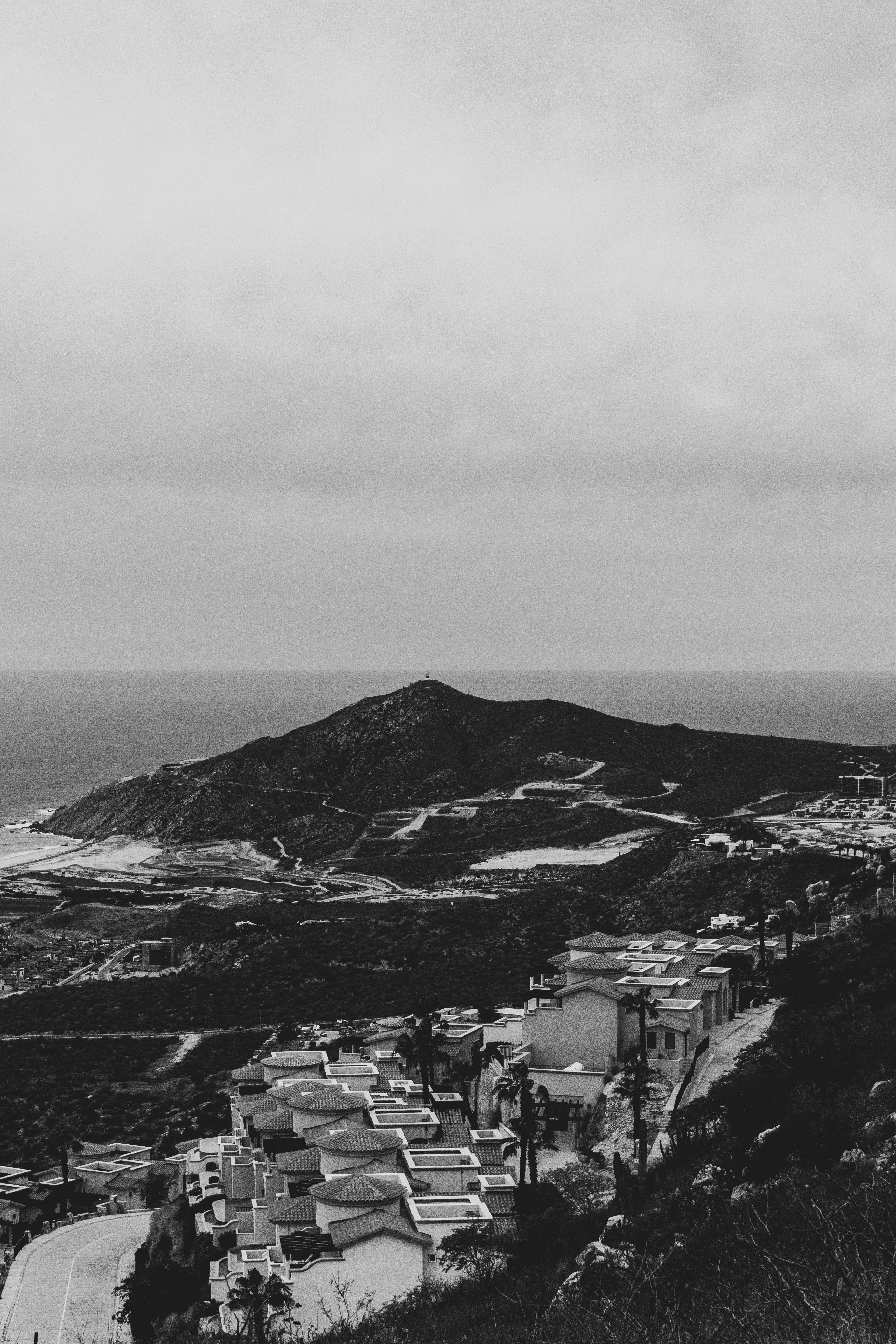Scenic view of Cabo San Lucas coastline with hills and condos in black and white.