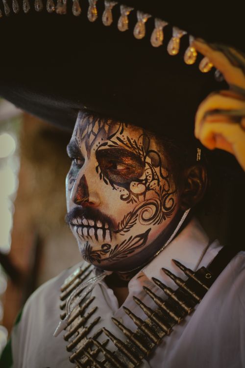Free Close-up of a man with intricate Dia de los Muertos face paint and traditional attire. Stock Photo