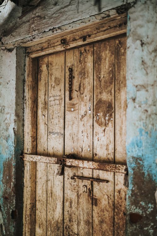 Free Close-up of a rustic, worn wooden door set in a blue-washed wall in Nagpur, India. Stock Photo