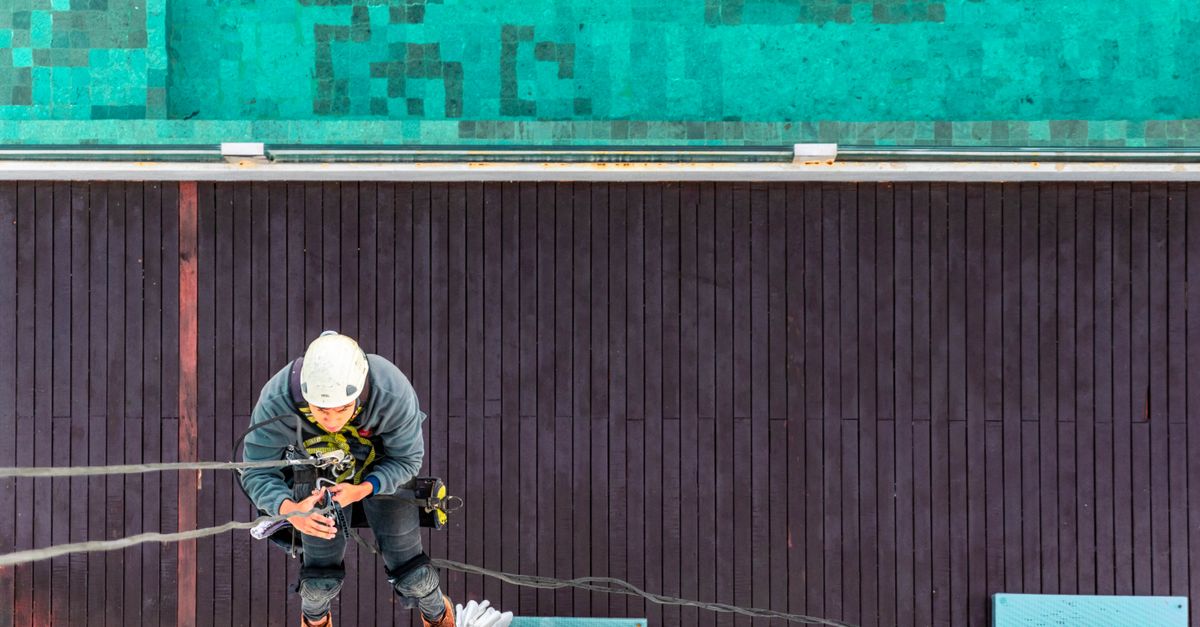 Berlins schwer erreichbare Fassaden: Wer den Stadtraum in Schuss hält 2 Ein Höhenarbeiter prüft am Dachrand seine Ausrüstung und befestigte Seile