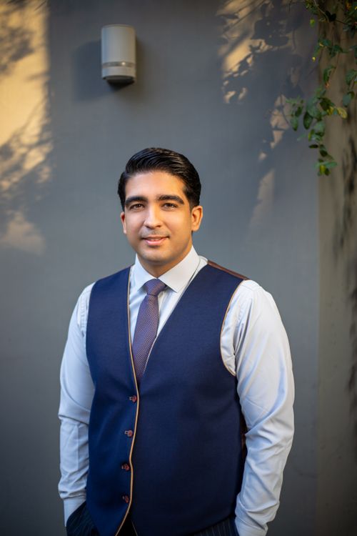 Free Confident businessman posing outdoors in a blue vest and tie, conveying professionalism and style. Stock Photo