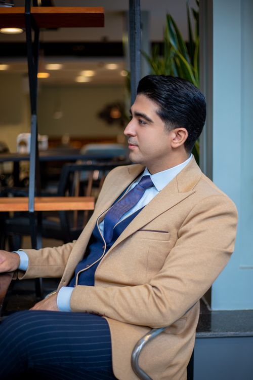 Free Portrait of a confident businessman sitting in a contemporary office setting, wearing a beige suit. Stock Photo