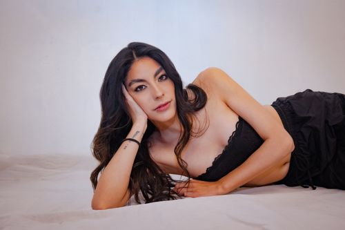 Free Sensual portrait of a woman in black lingerie lying on a bed with a warm expression. Stock Photo