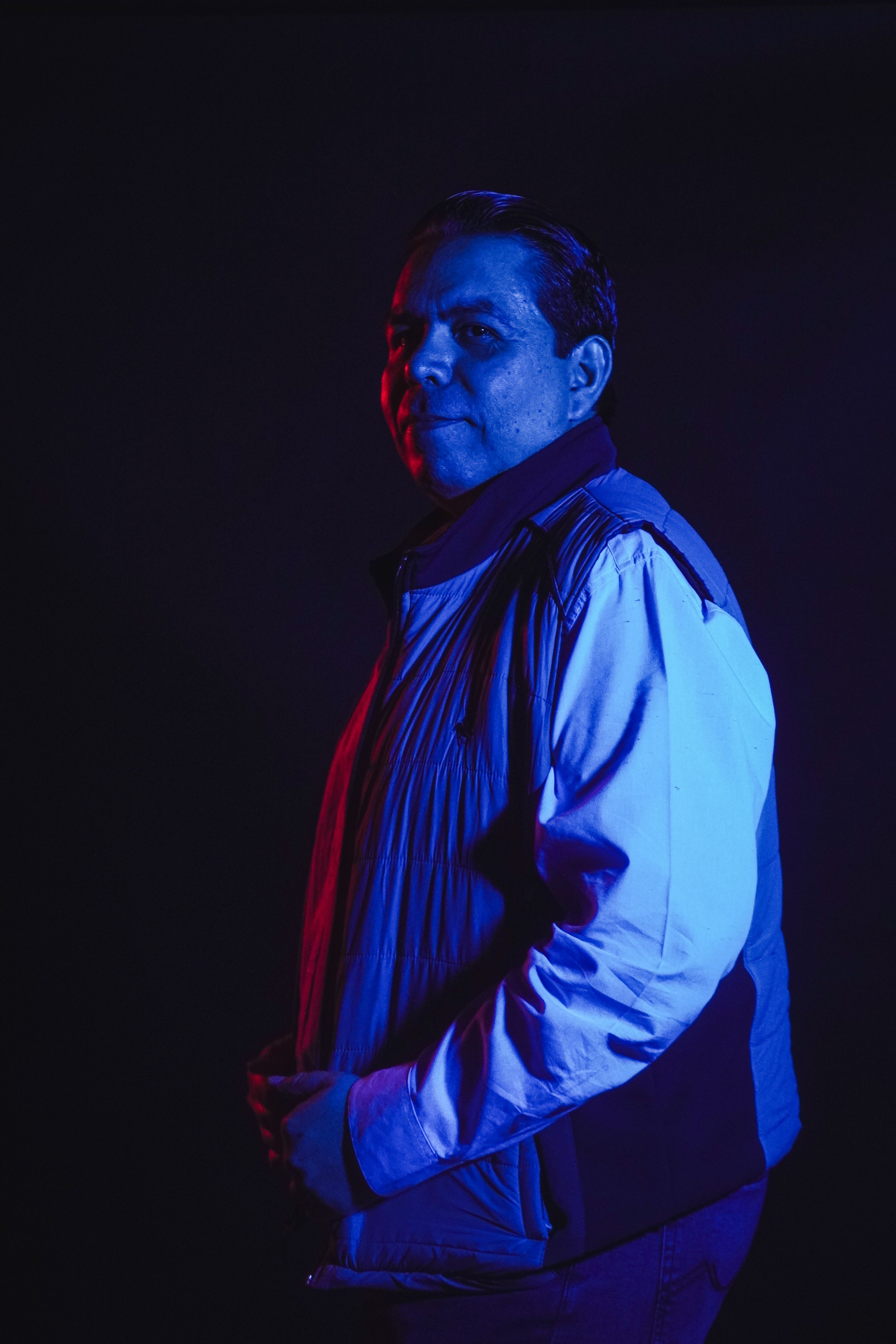Moody portrait of a man highlighted by blue and red lighting for a dramatic effect.