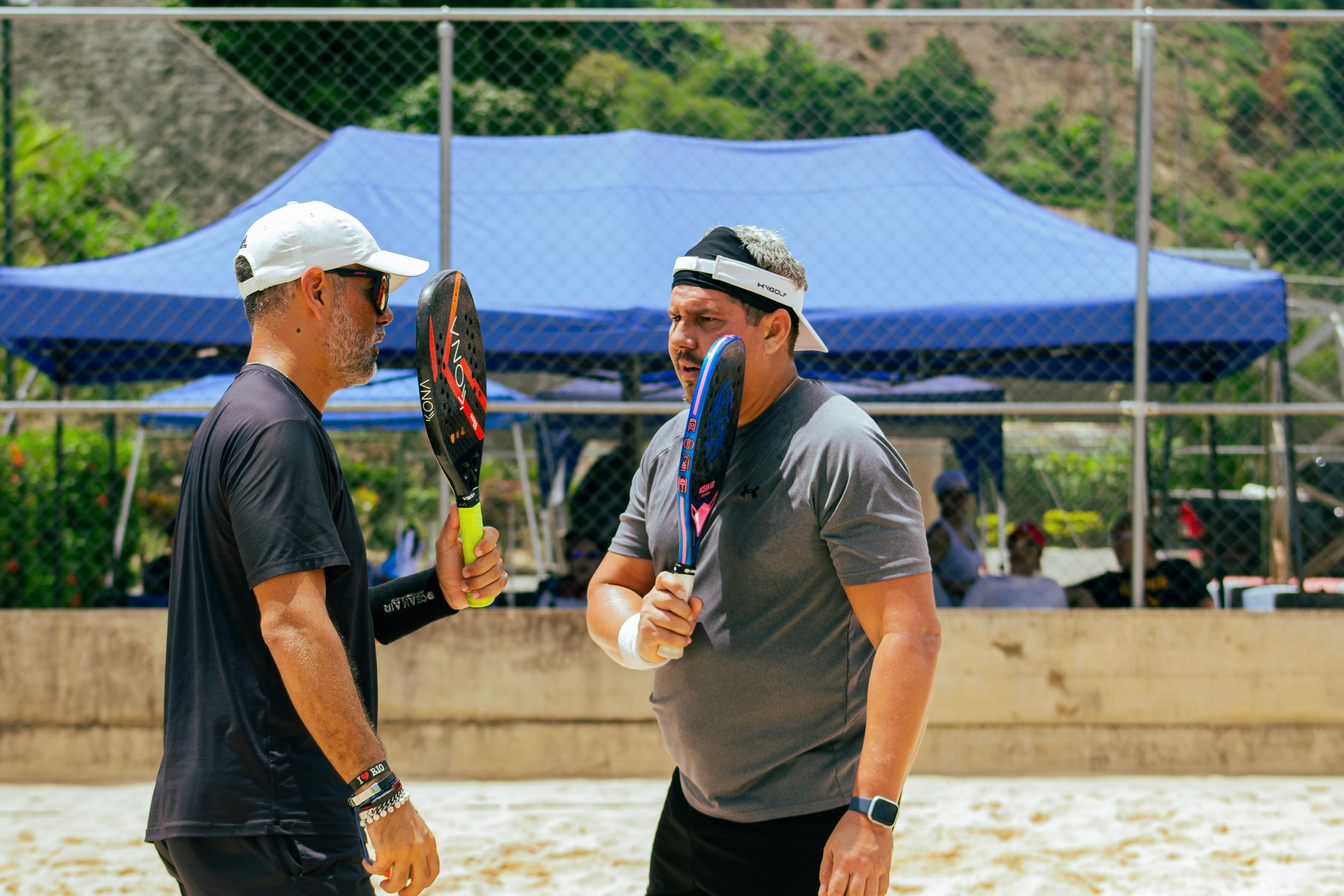 two men are talking to each other while holding tennis rackets