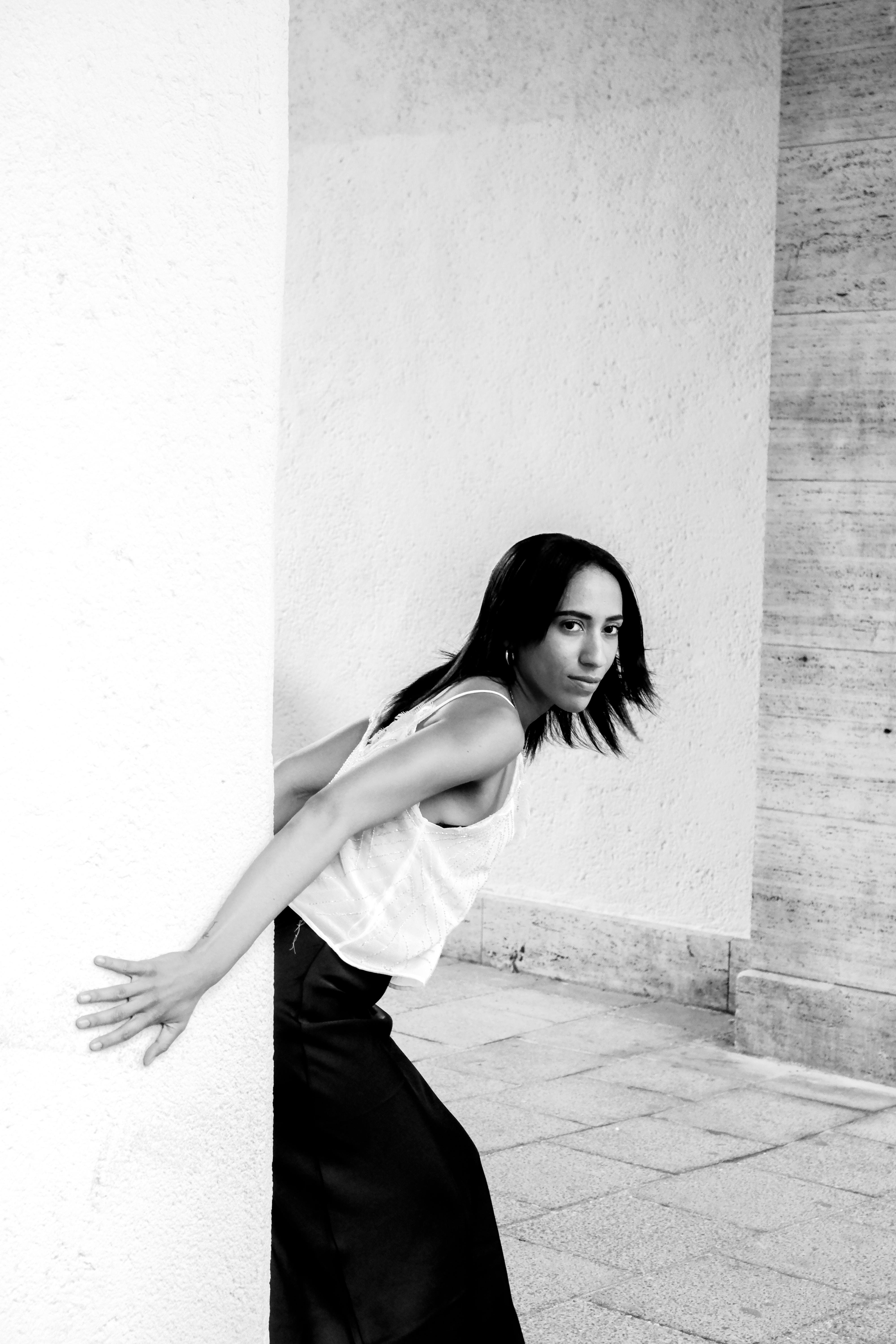 a woman leaning against a wall in a black and white photo