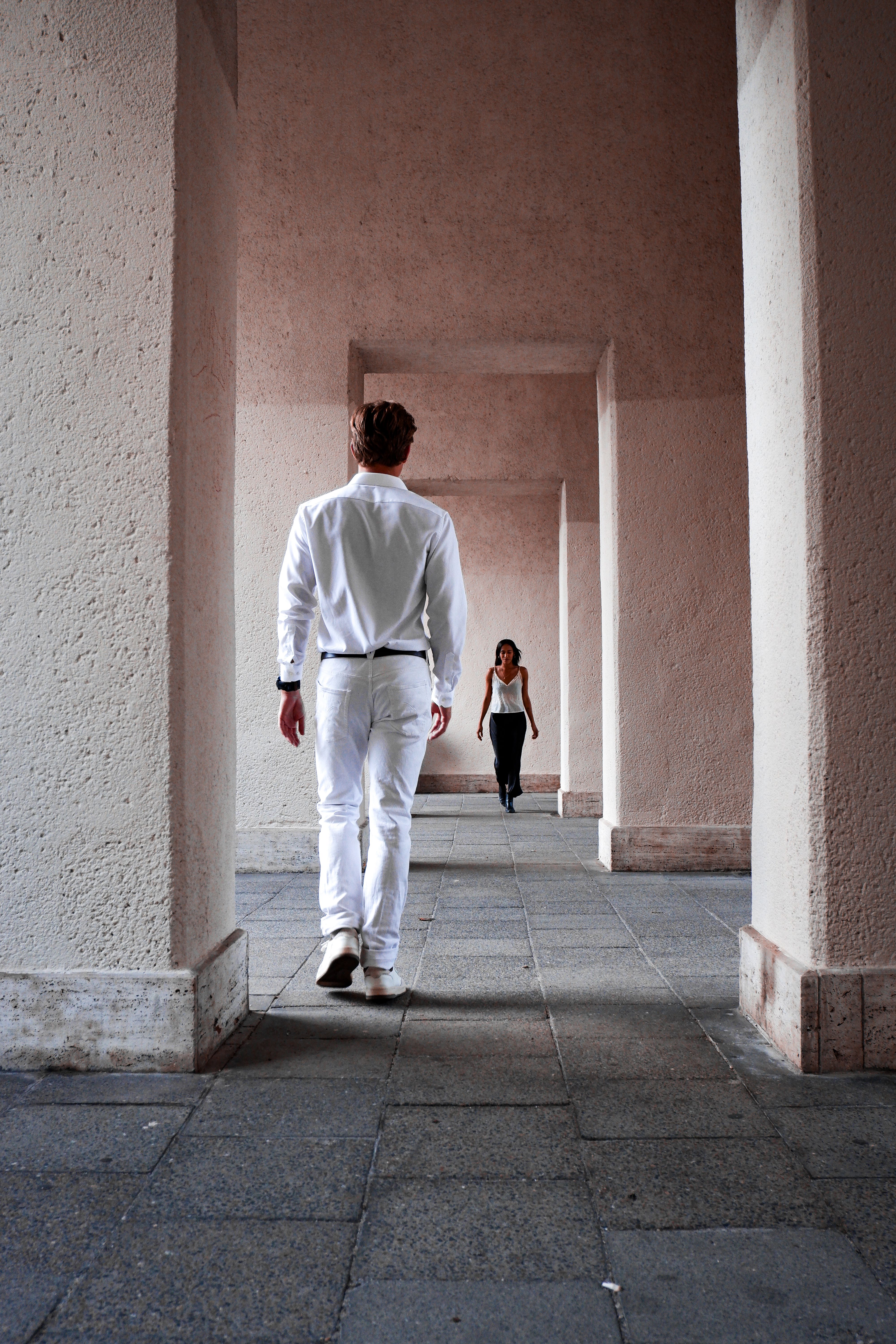 A Man and Woman Walking between the Columns · Free Stock Photo