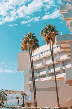 Sunlit building with palm trees against a bright blue sky in Palma de Mallorca, Spain.