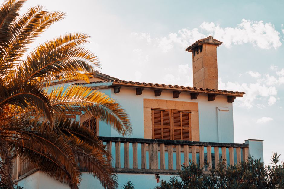 Mediterranean-style house with tiled roof, chimney and balcony under a sunny sky, typical of Cyprus residential architec