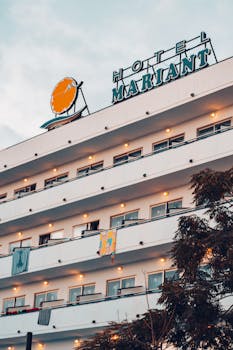 Exterior view of Hotel Mariant in Mallorca at dusk, showcasing its vibrant facade and signage.